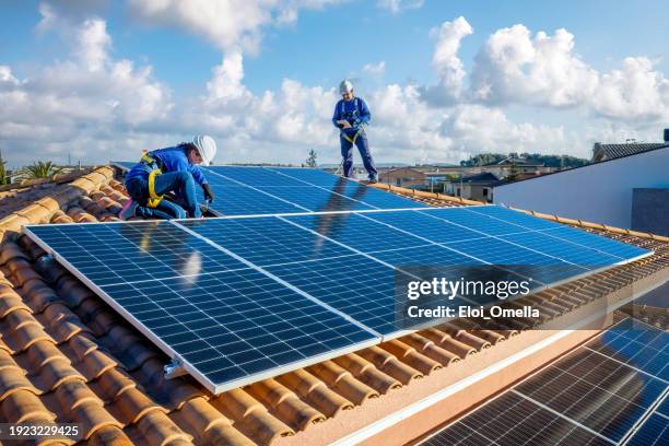 male and female workers installing solar panels in a roof - safety harness stock pictures, royalty-free photos & images