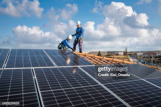 male and female workers installing solar panels in a roof - safety harness stock pictures, royalty-free photos & images