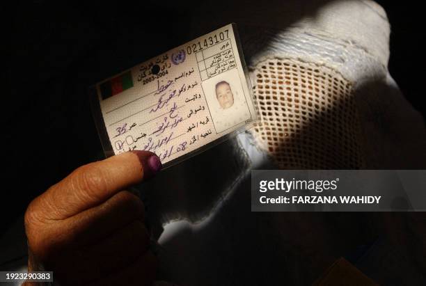 An Afghan woman displays her voter registration card in a polling station in Mazar-i-Sharif, 18 September 2005. In a relatively big turn out Afghans...
