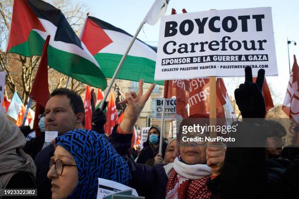 People are making the V sign, and a woman is holding a placard that reads 'Boycott Carrefour, sponsor of the war in Gaza'. Hundreds of people are...