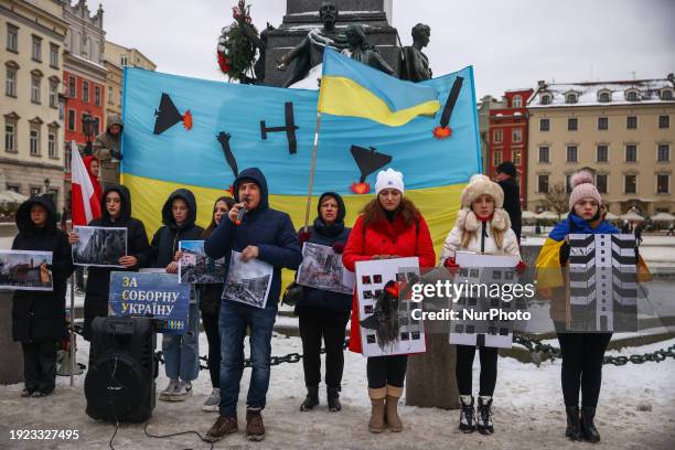 Protesters hold banners and Ukrainian flags during a daily demonstration of solidarity with Ukraine at the Main Square in Krakow, Poland on January...