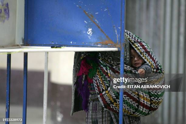 Guatemalan indigenous woman votes with her baby piggyback 04 November, 2007 in San Juan Comalapa, 80 km east from Guatemala City. Guatemalans voted...