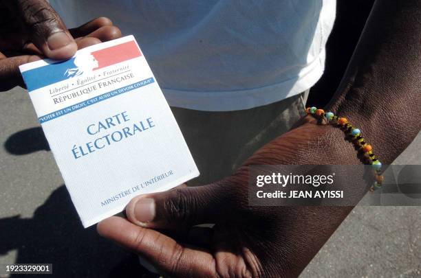 Man shows his polling card 22 April 2007 in Clichy-sous-Bois, Northeastern Paris. Some 44.5 million eligible voters choose 22 April 2007 a successor...