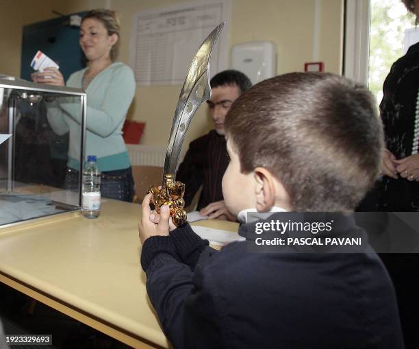 Boy holding a toy dagger looks at voters in a polling station during the 2nd round of French presidential election, 06 May 2007 in Toulouse,...