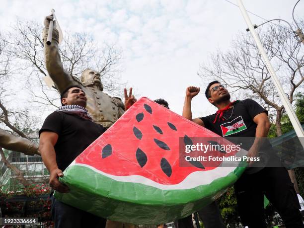 Protesters holding a watermelon, the fruit symbol of the Palestinian resistance, as dozens took to the streets in Lima to demonstrate as part of a...