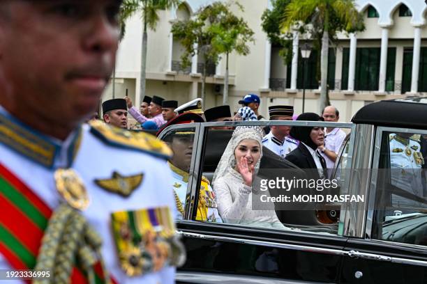 Prince Abdul Mateen and Yang Mulia Anisha Rosnah wave from their car during the wedding procession in Brunei's capital Bandar Seri Begawan on January...
