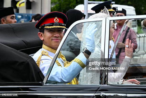 Prince Abdul Mateen and Yang Mulia Anisha Rosnah wave from their car during the wedding procession in Brunei's capital Bandar Seri Begawan on January...