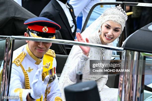 Prince Abdul Mateen and Yang Mulia Anisha Rosnah wave from their car during the wedding procession in Brunei's capital Bandar Seri Begawan on January...