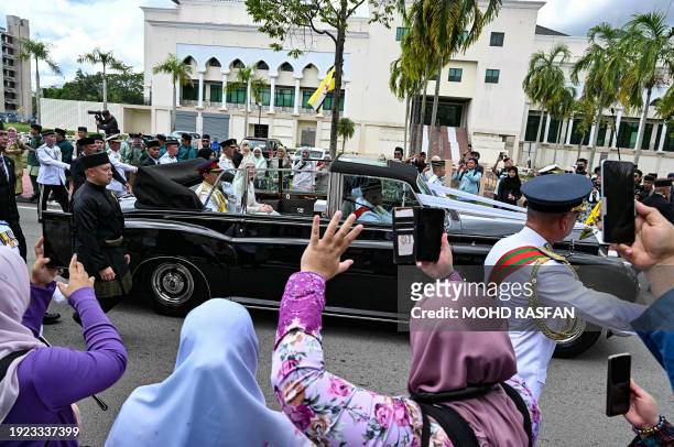 People cheer as Prince Abdul Mateen and Yang Mulia Anisha Rosnah sit in their car during the wedding procession in Brunei's capital Bandar Seri...