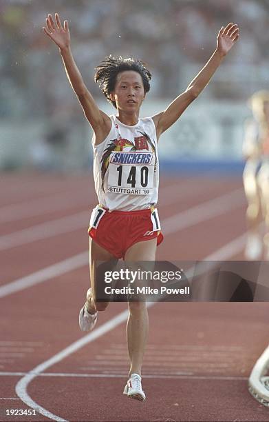 Junxia Wang of China raises her arms aloft as she crosses the line to win the 10,000 metres event during the World Championships at the Gottleib...