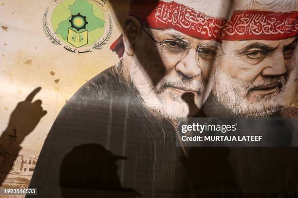 Supporters of pro-Iran factions gesture in front of a poster bearing an image of killed top Iranian commander Qasem Soleimani and Iraqi commander Abu...