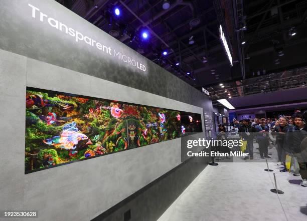 Attendees look at the world's first transparent MicroLED display, shown in front of an LCD, giving it a 3D effect, at the Samsung booth during CES...