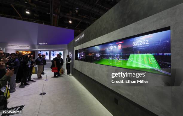 Attendees look at the world's first transparent MicroLED display, shown in front of an LCD, giving it a 3D effect, at the Samsung booth during CES...
