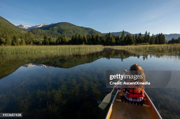 girl paddles canoe on tranquil lake - sport determination stock pictures, royalty-free photos & images