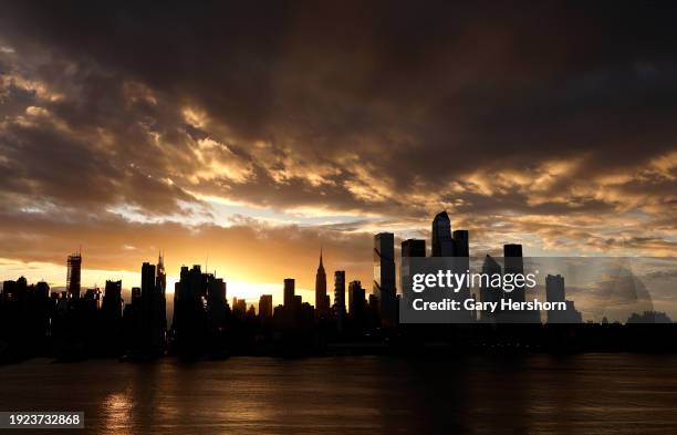 Storm clouds pass over midtown Manhattan and the Empire State Building as the sun rises in New York City on January 10 as seen from Weehawken, New...