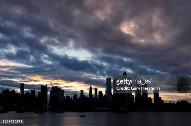 Storm clouds pass over midtown Manhattan and the Empire State Building as the sun rises in New York City on January 10 as seen from Weehawken, New...