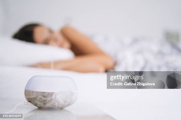 air humidifier aroma diffuser on background of sleeping young woman in bed at home - aromaterapia foto e immagini stock