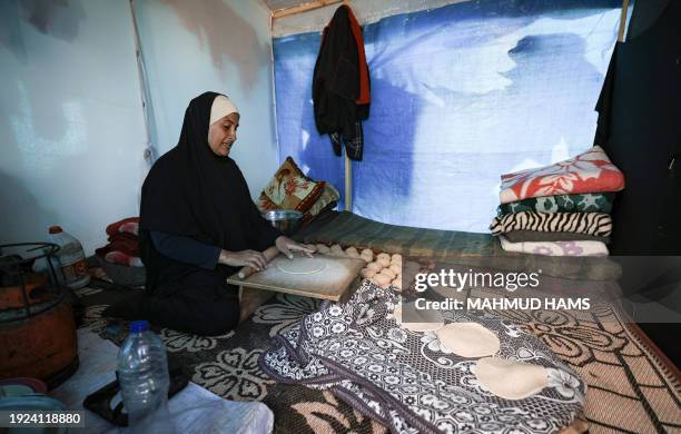 Displaced Palestinian woman prepares bread inside a tent at a makeshift camp along the Egyptian border, west of Rafah in the southern Gaza Strip on...