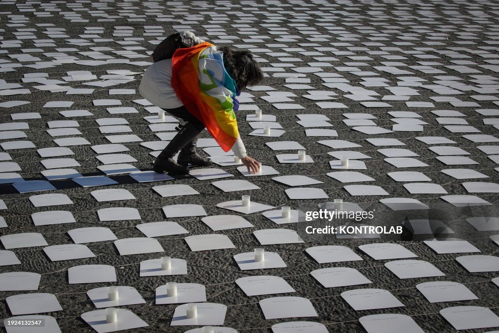 Activist wrapped with a peace flag as she lays a candle on...