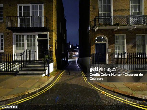 a narrow and dark street between two georgian-style houses at night in london, england, united kingdom. no people. - chelsea stock pictures, royalty-free photos & images