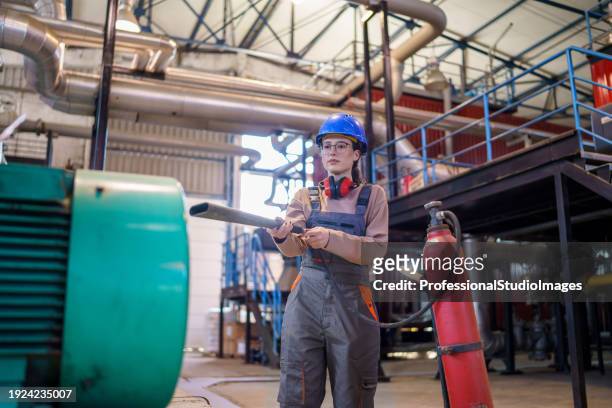 female worker in heating plant takes charge in firefighting effort - fire extinguisher inspection stock pictures, royalty-free photos & images