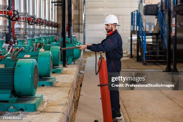 young heating plant worker calmly puts out fire - fire extinguisher inspection stock pictures, royalty-free photos & images