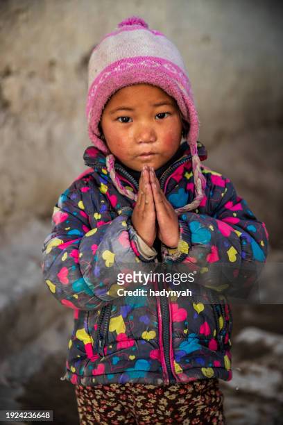namaste! portrait of tibetan little girl, upper mustang, nepal - prayer pose greeting fotografías e imágenes de stock