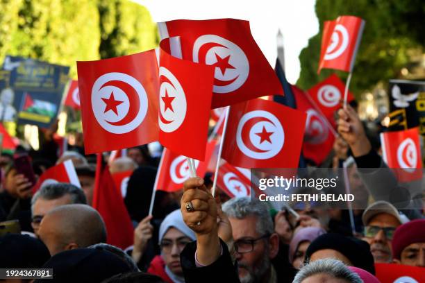Tunisians wave national flags during a protest marking the 14th year of the 2011 revolution and calling for the release of President's opponents on...