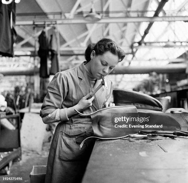 An upholstery worker holding a hammer on the production line at the Morris Motors car factory in Cowley, Oxfordshire, May 8th 1957.