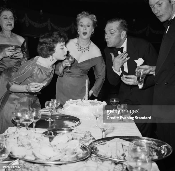 British actors Dorothy Tutin , Brenda de Banzie and Sir Laurence Olivier blowing out a candle on a cake during a party to celebrate the opening of...