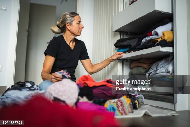 woman sorting and reducing clothing of her wardrobe at home - choosing clothes stock pictures, royalty-free photos & images