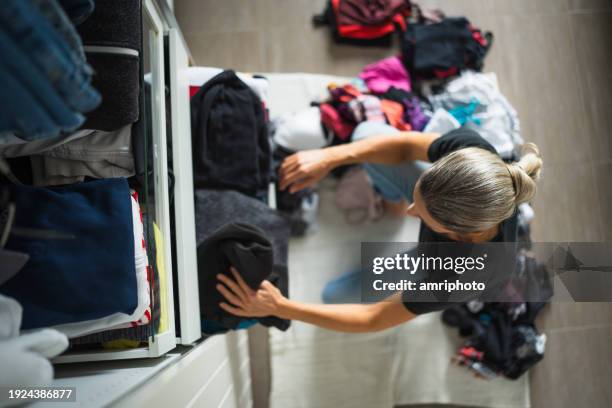 view from above at woman sorting clothes at home at open wardrobe - organising wardrobe stock pictures, royalty-free photos & images