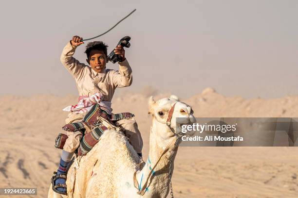 Bedouin boy holds his shoes while racing in the Zalaga on January 9, 2024 in Egypt. The annual 30 km camel race through the Sinai desert takes place...