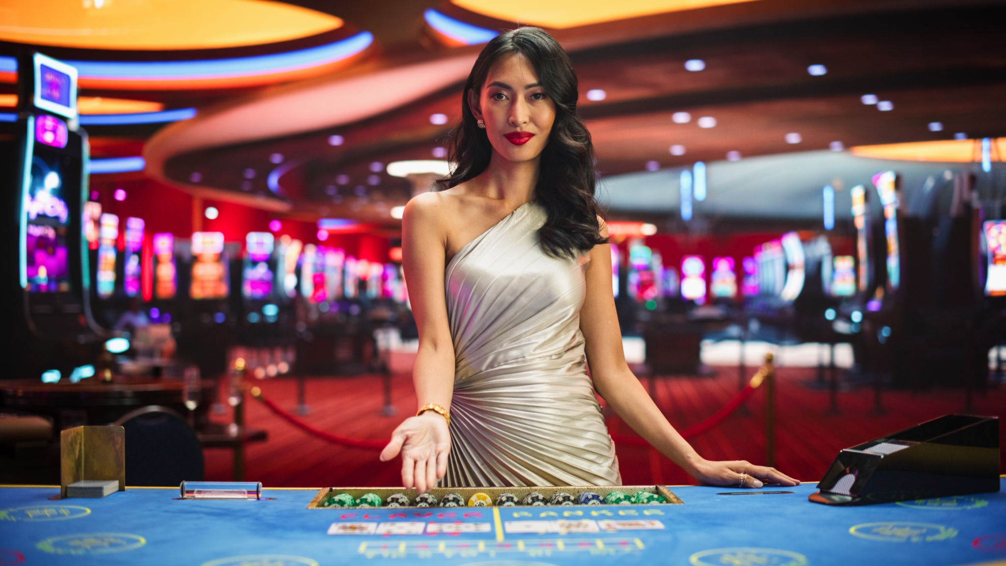 Portrait of a Profesional Asian Croupier in a Casino Dealing Playing Cards on a Baccarat Table. Game Dealer Opens and Reveals Winning Cards to the Audicence, Looking at the Camera in Online Casino Portrait of a Profesional Asian Croupier in a Casino Dealing Playing Cards on a Baccarat Table. Game Dealer Opens and Reveals Winning Cards to the Audicence, Looking at the Camera in Online Casino