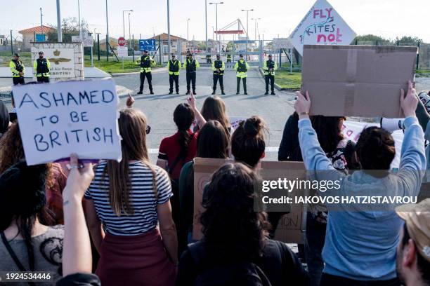 Peace protesters face police officers standing guard in front of the gates of the Royal Air Force Akrotiri base, a British overseas territory near...