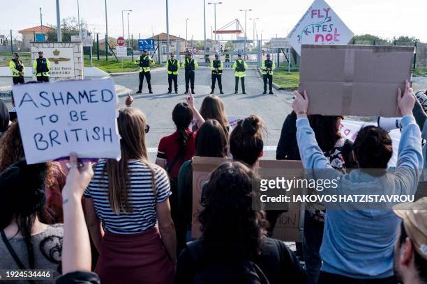 Peace protesters face police officers standing guard in front of the gates of the Royal Air Force Akrotiri base, a British overseas territory near...
