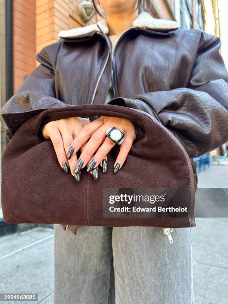 Samia Laaboudi wears a cocoa suede mini tote bag, a finger ring, black and white shiny / glitter nail polish, during a remote street style fashion...