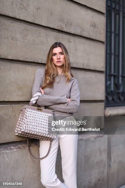 Zita D'Hauteville wears a gray wool pullover / top, a Fendi gray and white fluffy bag, white pants, during a street style fashion photo session, on...