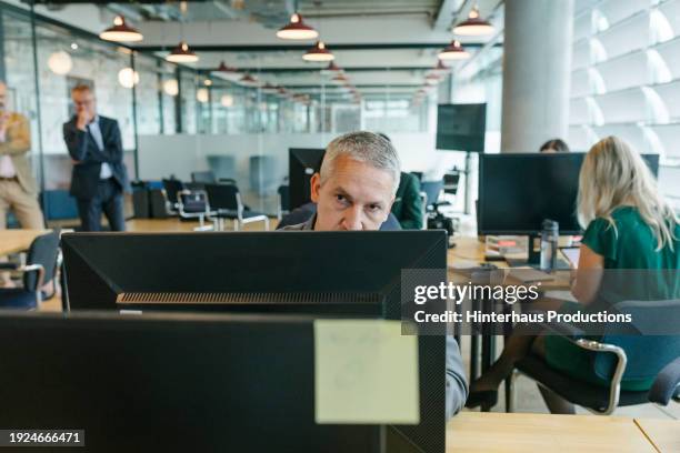 man thinking while looking at computer monitor in office - staring at screen stock pictures, royalty-free photos & images