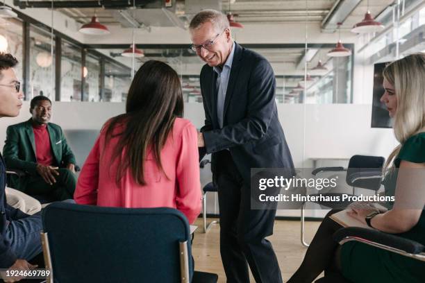 office manager interacting with staff members during business meeting - mature man smiling 40 44 years blond hair stock pictures, royalty-free photos & images