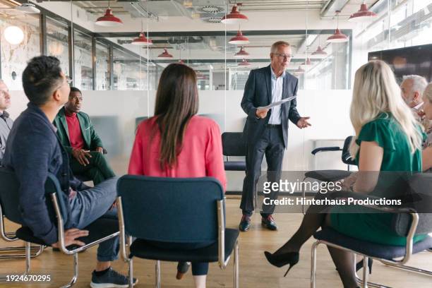 office manager holding meeting with employees - mature man smiling 40 44 years blond hair stock pictures, royalty-free photos & images
