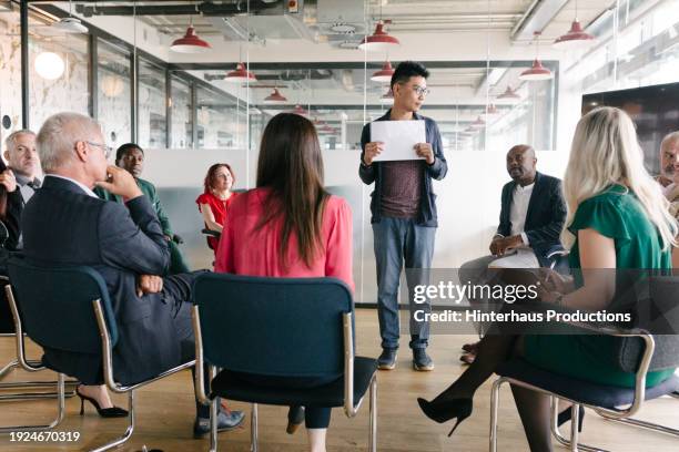 office associate standing in middle of room giving presentation - mature man smiling 40 44 years blond hair stock pictures, royalty-free photos & images