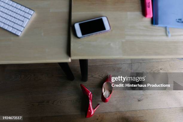 two red high heel shoes under office desk - high heel stock pictures, royalty-free photos & images