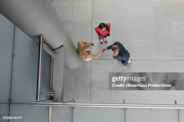aerial view of business associates shaking hands - office aerial interior stock pictures, royalty-free photos & images