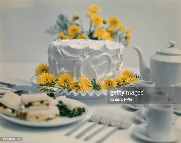 An Italian meringue frosting cake decorated with dandelion, near a tea set, US, 1997.