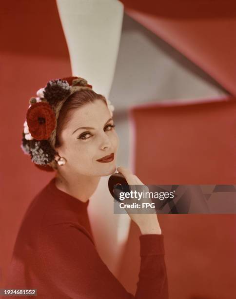 Fashion model wearing knitted hat with knitted flowers and pom poms, US, 1997.