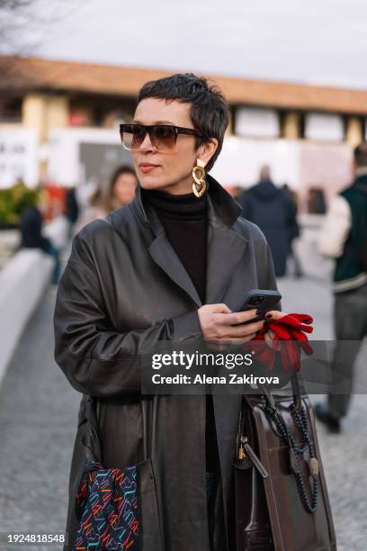 Mila Ushakova wearing a brown leather coat and red gloves is seen during Pitti Immagine Uomo 105 at Fortezza Da Basso on January 10, 2024 in...