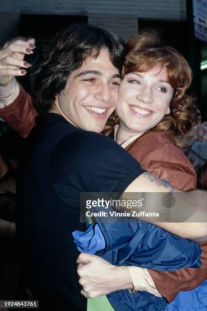 American actor Tony Danza, wearing a black t-shirt, embraces his 'Taxi' co-star, American actress Marilu Henner, who wears a brown jacket and holds a...
