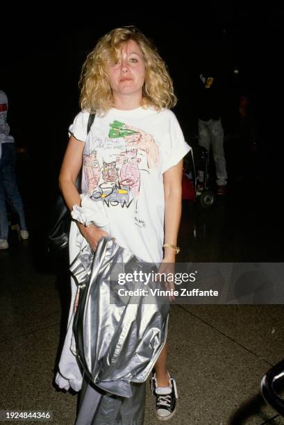 American actress Patti D'Arbanville, wearing a 'Housing Now!' campaign t-shirt, and holding a silver coat, at the Los Angeles International Airport...