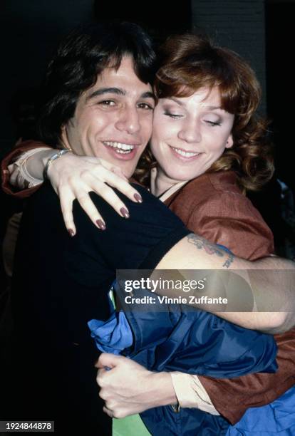 American actor Tony Danza, wearing a black t-shirt, embraces his 'Taxi' co-star, American actress Marilu Henner, who wears a brown jacket and holds a...
